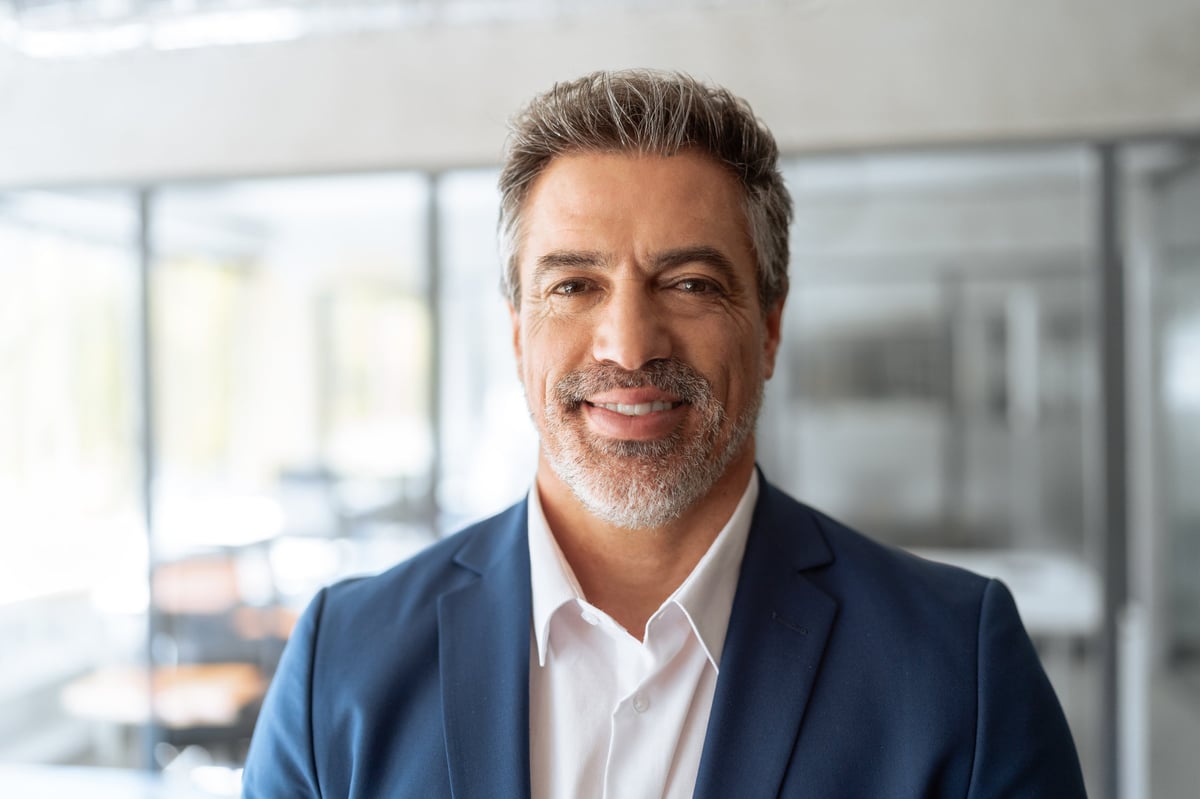 Headshot of a confident senior business leader smiling at camera in suit in office