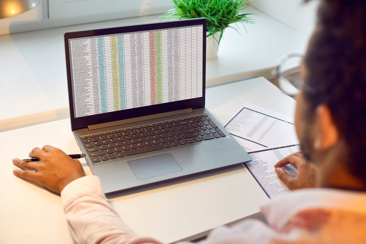 Professional working on laptop with financial data on modern notebook computer