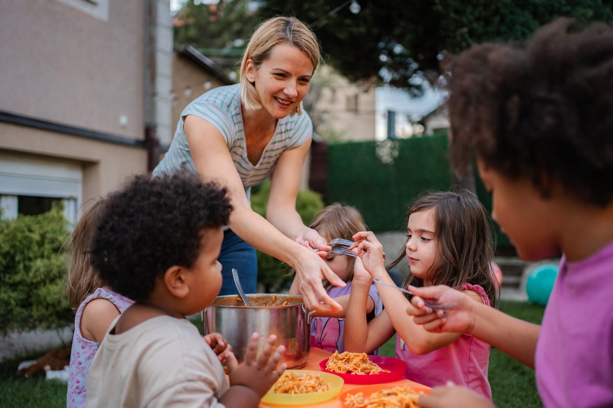 Family serving food at a community gathering around a garden table
