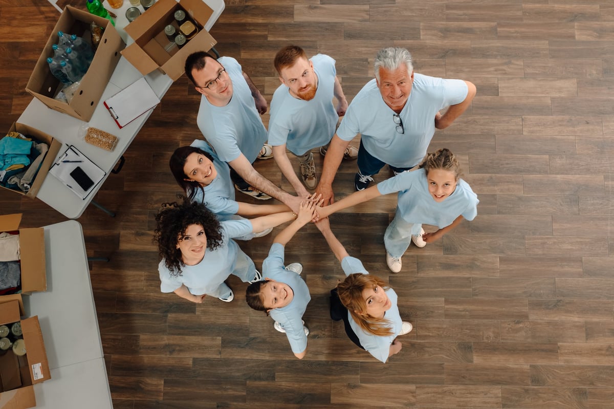 Diverse group of smiling volunteers stacking hands at a community center symbolizing teamwork and unity